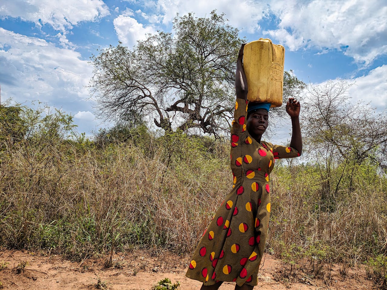hero-img-01 Woman carrying a container on her head in rural Kitgum, Uganda.