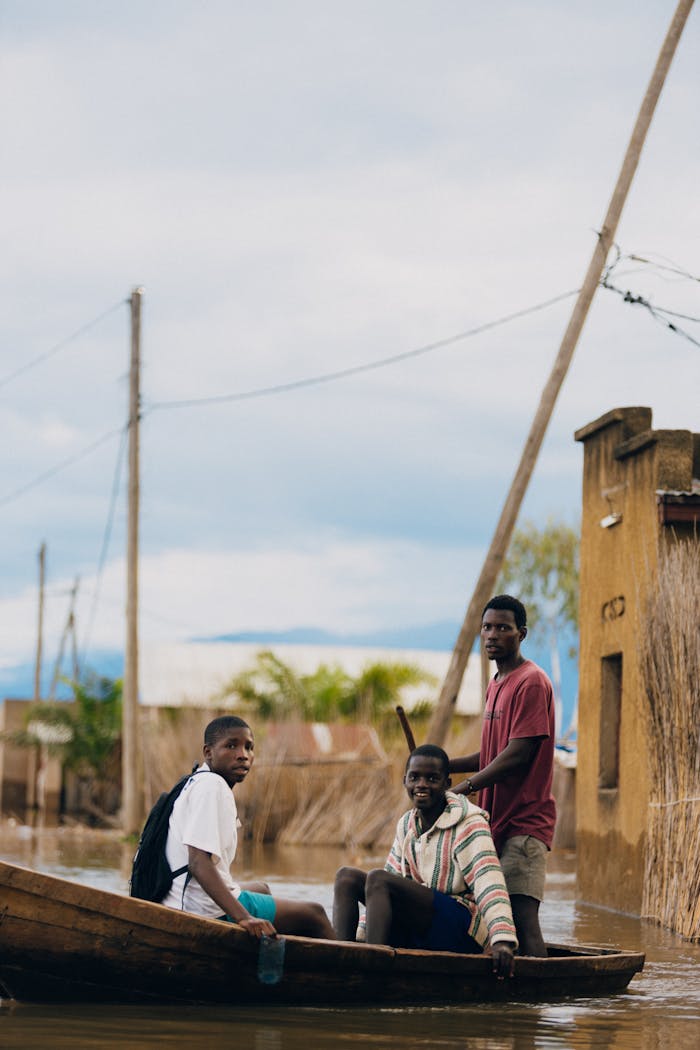why-choose-us Three men in a wooden boat navigating a flooded area, showcasing resilience and community.